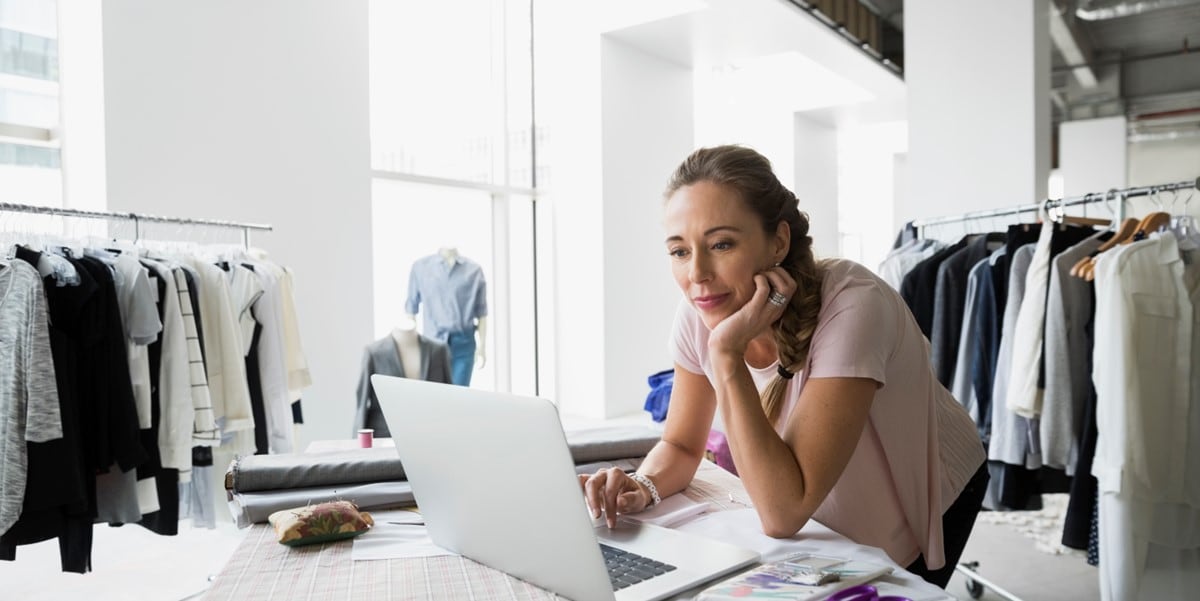 woman in shop, looking at laptop on a table