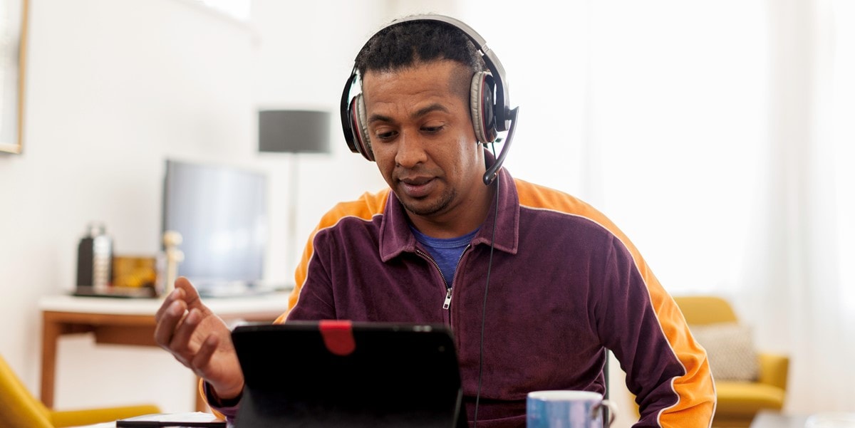 man working at a desk, attending virtual meeting with headset