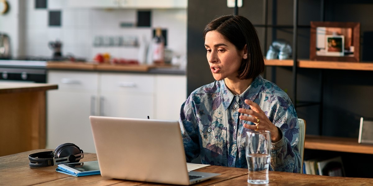 woman in office, attending virtual meeting from laptop