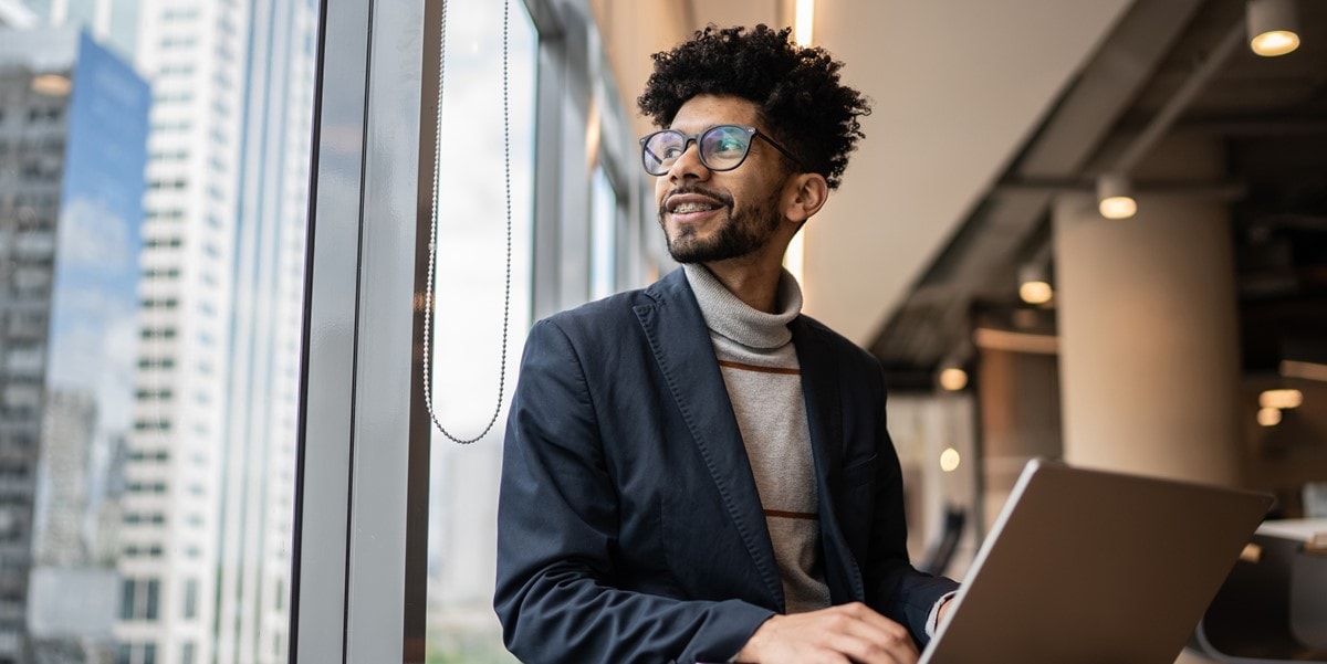 man in suit, sitting with laptop, looking out window