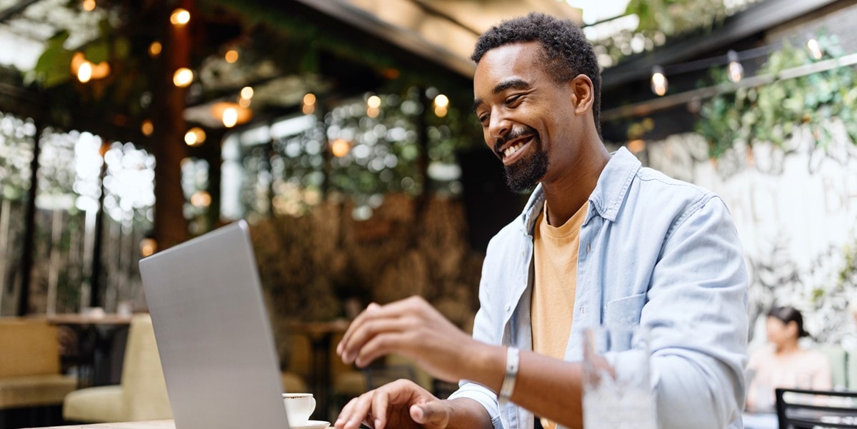 man working on laptop sitting at a cafe table