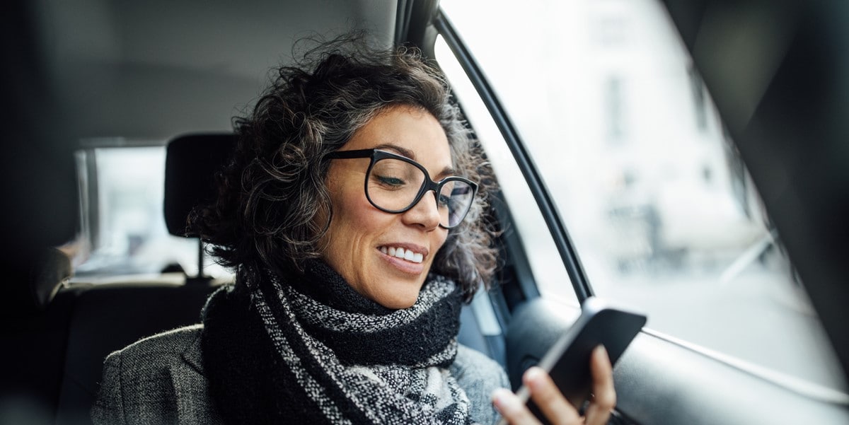 traveler in car, looking at cell phone in hand