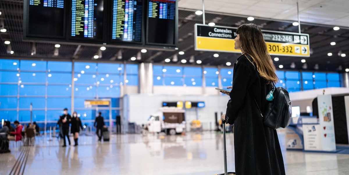 travel in an airport with luggage, looking at flight information